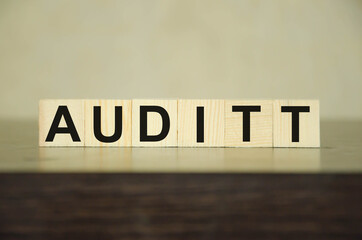 the word audit is written on wooden cubes that lie on a black table
