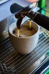 The process of making coffee in white ceramic cup on professional coffee machine.