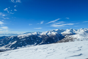 Obraz premium A panoramic view on snow capped Alps in Austria, seen from Katschberg Ski Resort in Austria.The slopes are covered with fresh, powder snow. Idyllic winter landscape. Sunny day
