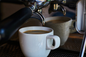 The process of making coffee in white ceramic cup on professional coffee machine.