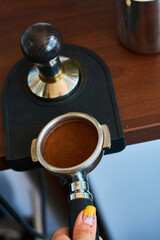The process of temper coffee in holder, making espresso on coffee machine.
