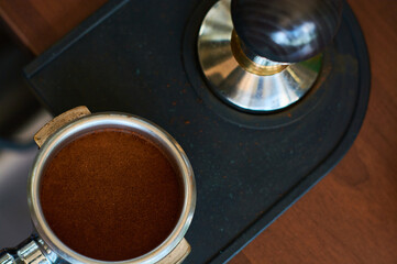 The process of temper coffee in holder, making espresso on coffee machine.