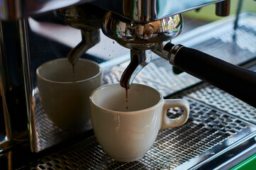 The process of making coffee in white ceramic cup on professional coffee machine.