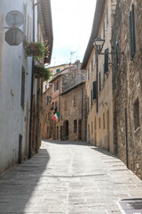 Fototapeta na wymiar Authentic street with view in small village in tuscany in Italy with brown stones houses