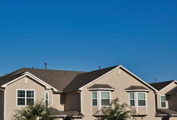 Townhome rooftops in the suburbs in a city subdivision under a clear blue sky with copy space above.