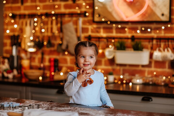 Young girl in blue dress cooking at the kitchen with Christmas background.