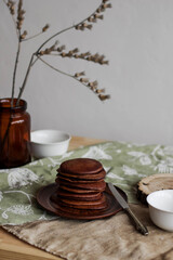 Chocolate pancakes with honey on a brown ceramic plate. Sweet breakfast on a table. Bright interior. Minimalism.