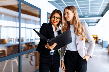 Young business women discussing documents while walking down the hallway in the office © Shopping King Louie
