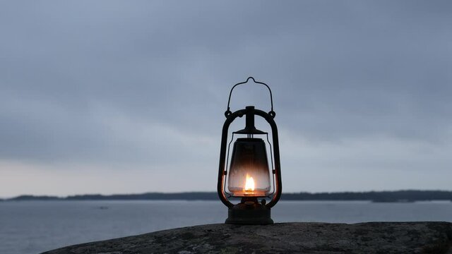 Mystical scene with old kerosene lamp. Vintage lantern. Sea background. Cloudy day.