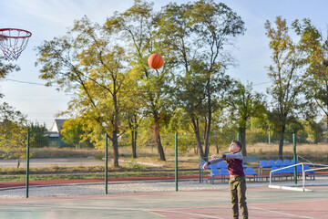 A boy throws a basketball on the playground.