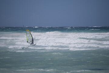
windsurf board in the middle of the waves on a sea with different blue tones