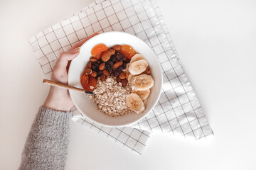 Carbohydrate healthy breakfast. Oatmeal with dried fruits on a white plate. View from above