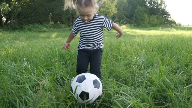 baby daughter playing football soccer in the park on the grass. happy family dream kid concept. little girl child play ball outdoor lifestyle sports in park healthy. kid play with son into ball fun