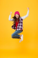 Fototapeta na wymiar hipster look. cheerful child in knitted hat. denim fashion style. school girl on yellow background. full of energy. kid fashion and beauty. teenager jumping in casual style clothes. happy childhood