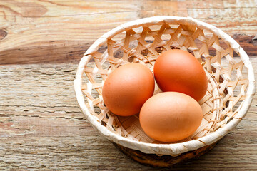 cracked eggs in a wicker plate on a wooden table.