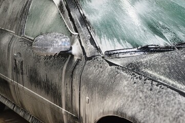 Car body is covered with soap foam to remove dirt from the body