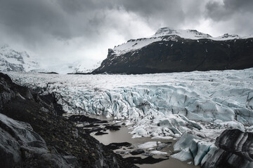 Fototapeta na wymiar Svínafellsjökull glacial tongue panorama with glacial lagoon and dramatic clouds and mountains 