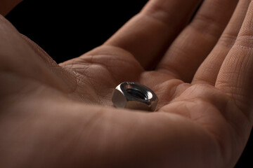 screw-nut in hands on a black background
