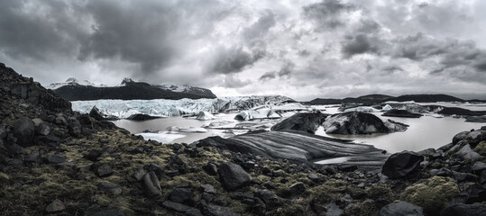 Svínafellsjökull glacial tongue panorama with glacial lagoon and dramatic clouds and mountains
