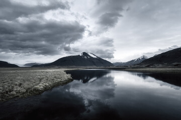 Iceland reflection of mountains, glacial tongues, and dramatic storm clouds at sunset
