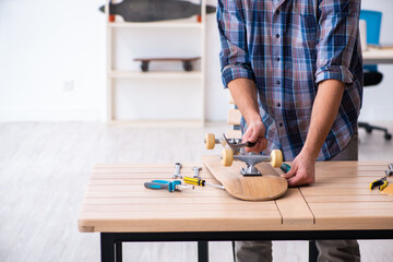 Young man repairing skateboard at workshop