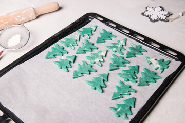 Rolled out dough on a baking tray for Christmas cookies in the form of Christmas trees. Preparing for the celebration of Christmas. Horizontal orientation