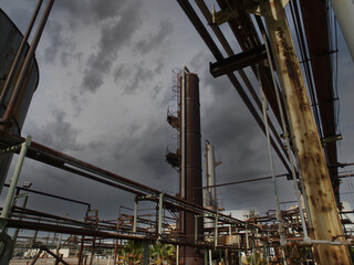 Fototapeta premium View of old oil refinery pipes with thunderstorm sky.