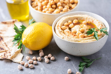 Hummus, chickpea dip, olive oil, raw beans, smoked paprika, pita on grey authentic background. Middle eastern, jewish cuisine or arabic dishes. Macro view. Copy space. Vegan, vegetarian food concept