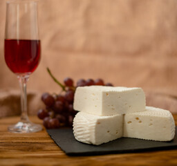 Goat cheese, grapes and wine lie on a wooden table. Cheese at home.