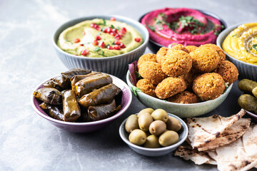 Traditional Middle Eastern assorted meze: hummus, pita, olives, pistachios, dolma, falafel balls, pickles, babaganush, vegetables, pomegranate, eggplants. Top view. Banner. Copy space. Arab meal