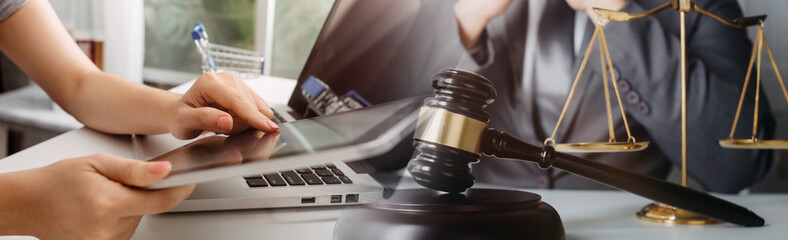 Justice and law concept.Male judge in a courtroom with the gavel, working with, computer and docking keyboard, eyeglasses, on table in morning light