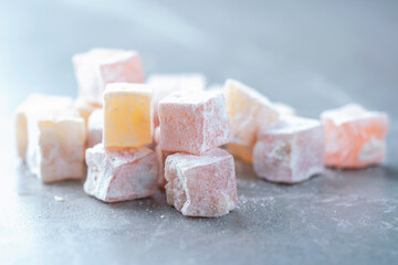 Turkish delight - rahat lokum or lokum with sugar powder on grey background. Traditional eastern cuisine. Traditional middle eastern sweets. Jewish, turkish, arabic national dessert. Turkish delight