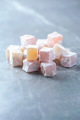 Turkish delight - rahat lokum or lokum with sugar powder on grey background. Traditional eastern cuisine. Traditional middle eastern sweets. Jewish, turkish, arabic national dessert. Turkish delight