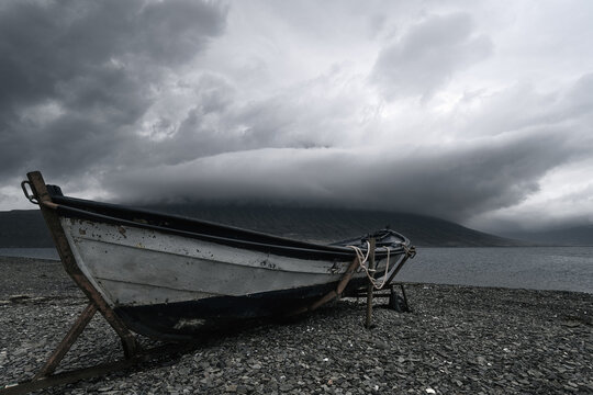 Old Row Boat And Dramatic Storm Clouds Around The Peak Of Hólmatindur