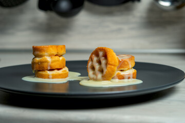 Soft waffles soaked in condensed milk with lie on gray plates in the kitchen