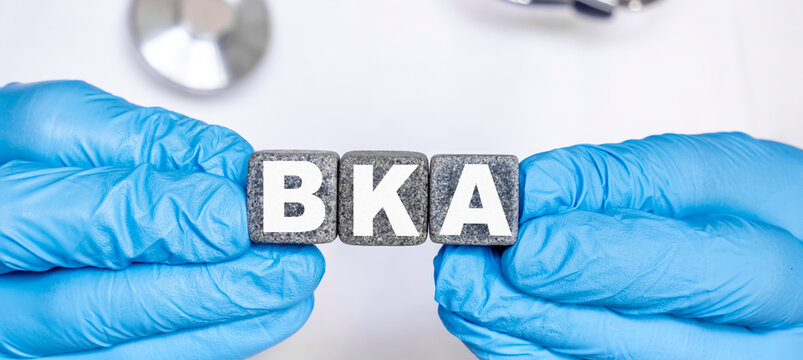 BKA Below the knee amputation - word from stone blocks with letters holding by a doctor's hands in medical protective gloves