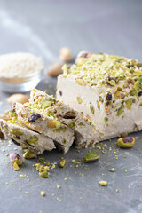 Sesame halva with pistachios on grey background. Top view. Copy space. Traditional middle eastern sweets. Jewish, turkish, arabic national dessert. Turkish delight