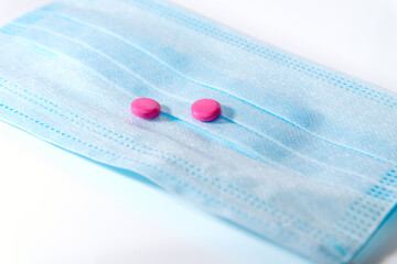 The concept of pills from  COVID-19. Medical mask on a white background. Medicinal pills against...