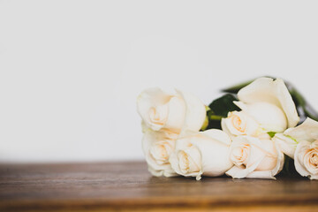 Composition with white roses on white and wooden background