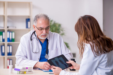 Old male doctor radiologist and his young female assistant in th