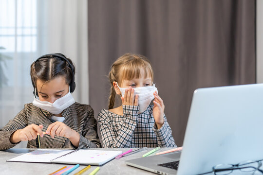 Home schooling learning during virus pandemic - two children drawing in the living room, wearing surgical face masks to protect them from the virus. - Powered by Adobe