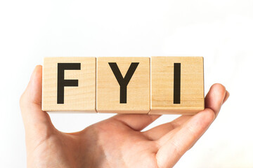 Hand holds wooden cubes with letters fyi. Business concept image.