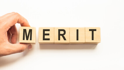 Word merit. Wooden small cubes with letters isolated on white background with copy space...