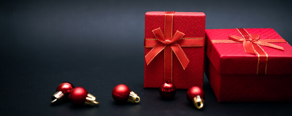 Red gift box with balls for decorating a Christmas tree on a black background