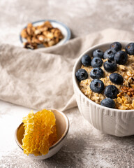 Healthy breakfast bowl: oatmeal with blueberries, nuts and honeycomb piece. Oat flakes with berries.