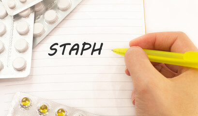 Text staph on white background. There are various pills and vitamins around. Medical concept