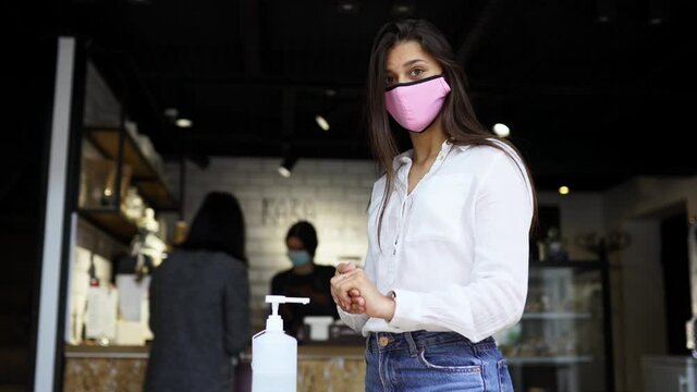 Woman using sanitizer gel cleans hands of coronavirus virus at cafe.