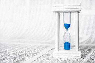 Hourglass on laptop concept countdown to deadline. Against the background of financial statements, tables with numbers. Business finance concept