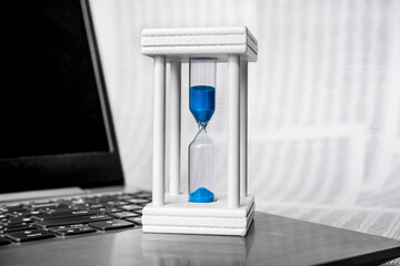 Hourglass on laptop concept for time management and countdown to deadline. Against the background...
