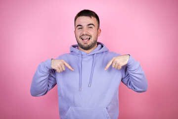 Young handsome man wearing casual sweatshirt over isolated pink background looking confident with smile on face, pointing oneself with fingers proud and happy.